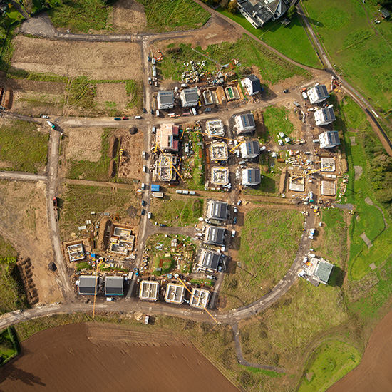 Amtliche Vermessung, Bodenordnung: Drohnen-Bild eines Baufeldes mit mehreren Häusern von oben